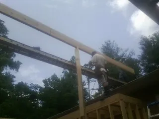 Carpenter setting a ridge beam over a new addition frame — Ice Dam Removal by Roofing Brothers in Owego