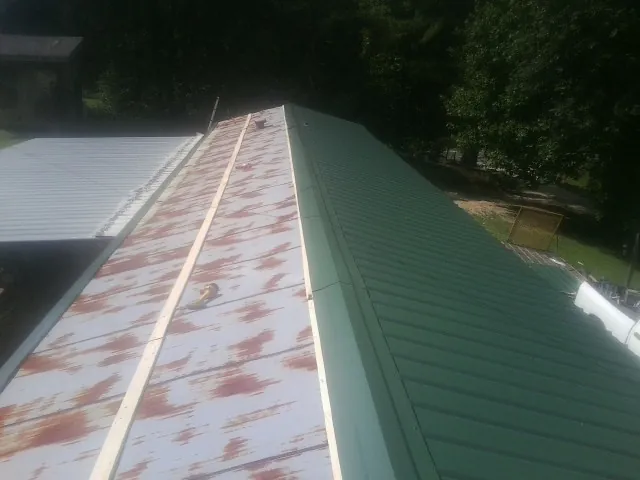 Old rusted panels beside newly installed green metal roofing — Wind Damage Roof Repair by Roofing Brothers in Owego