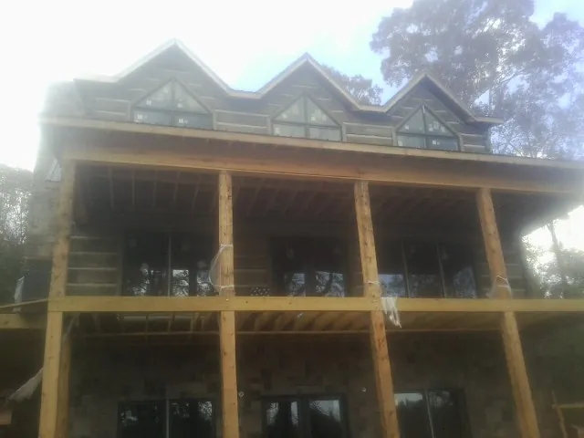 Dormers and porch framing on a large log home under construction — Roof Coating work by our crew in Owego