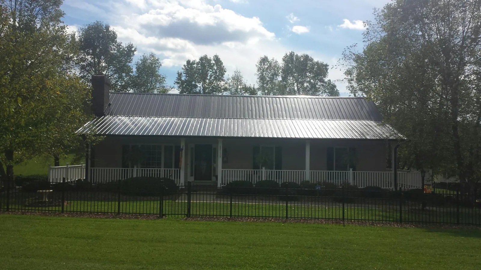 Gray metal roof on a brick ranch with a full width front porch — Gutter Guard Installation work by our crew in Owego