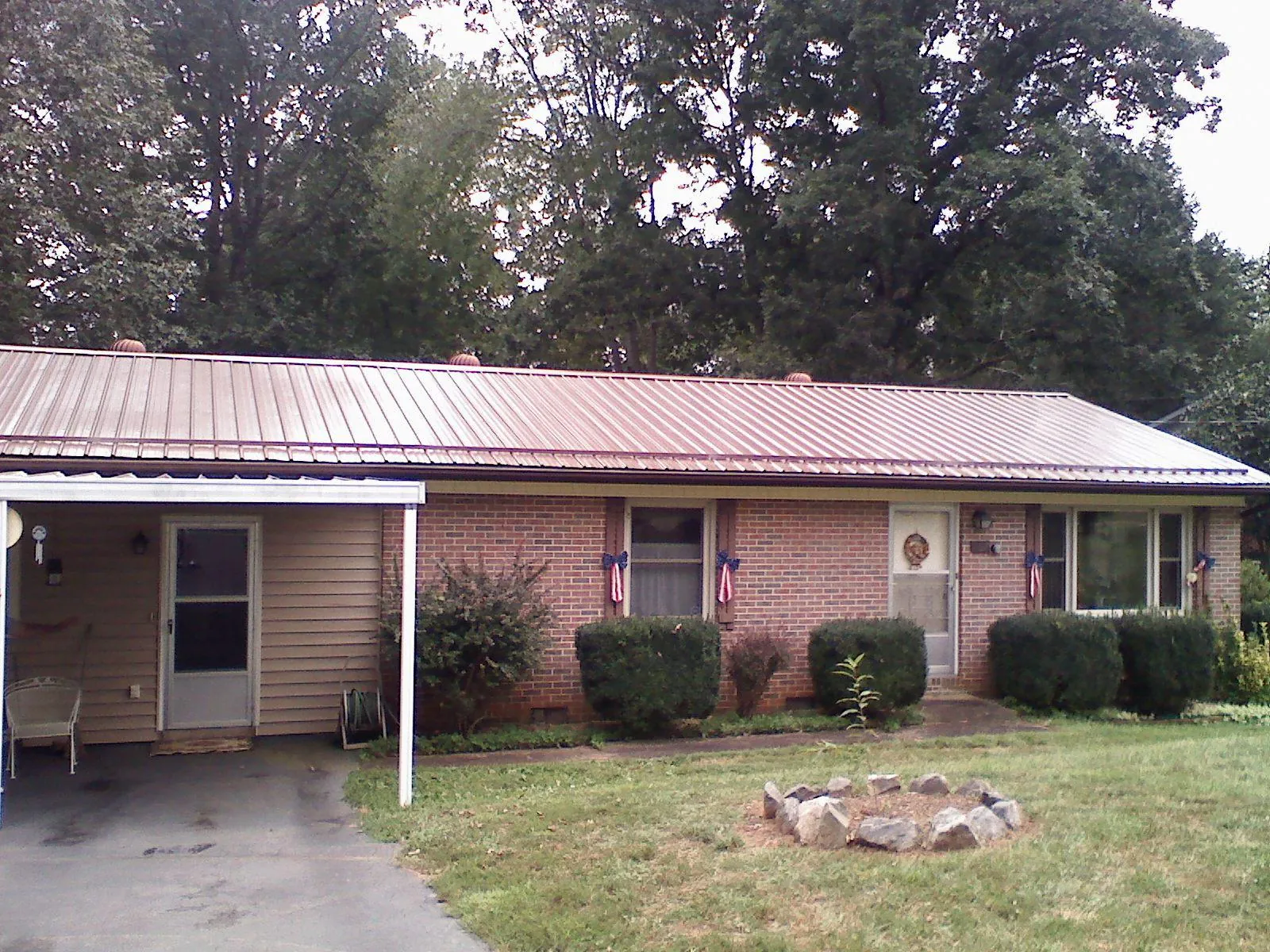 Bronze metal roof and carport on a brick ranch home — Roof Repair work by our crew in Owego