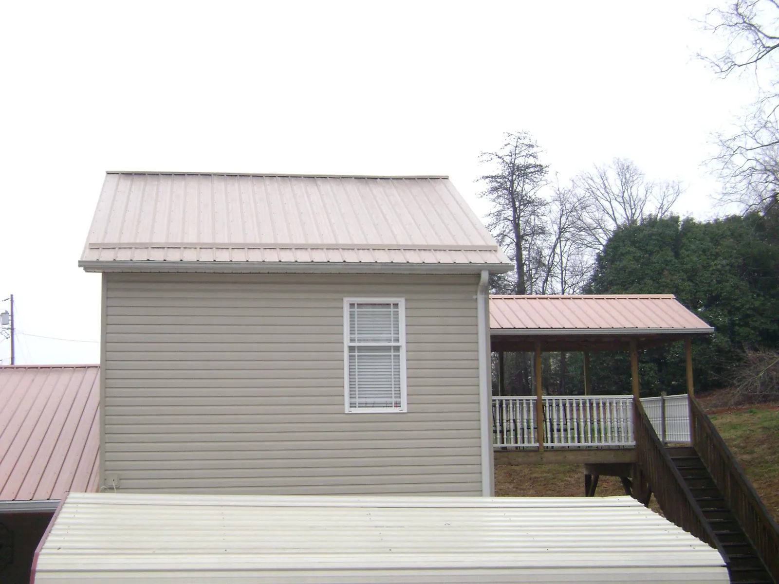 Tan metal roofs on a two story addition and attached porch, from a Roof Replacement job in Owego